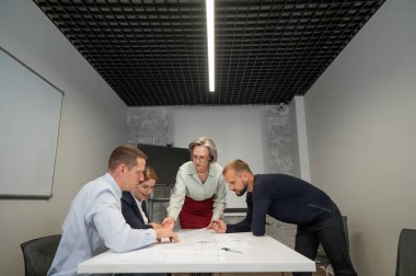 The female boss evaluates the work of subordinates. Designers engineers at a meeting