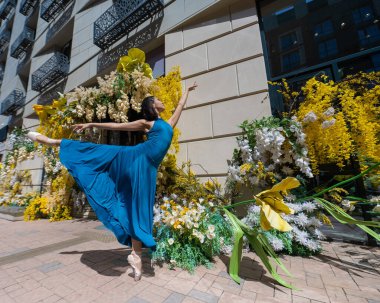 Çiçeklerle süslenmiş bir binanın arka planında poz veren güzel bir Asyalı balerin.