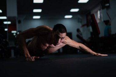 Spor salonunda şınav çeken kaslı üstsüz bir adam.