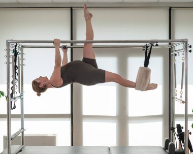 Hamile bir kadın bir reformcu üzerinde pilates yapıyor. Hava jimnastiği