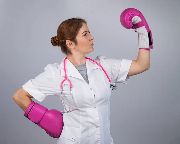 Woman doctor in pink boxing gloves on a white background