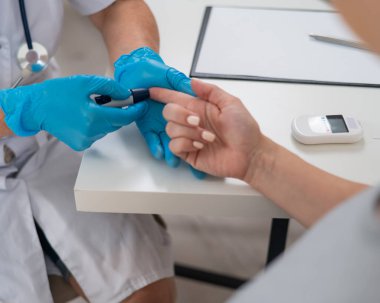 Doktor hamile bir hastanın kan şekerini ölçüyor. Gebelik Diyabet