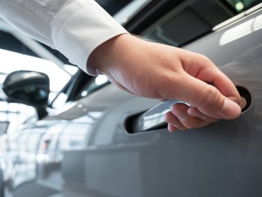 Adamın biri parmak iziyle arabanın kapısını açıyor. Bütünleşik kulp