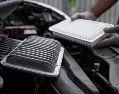 Araba motorundaki hava filtresini değiştiriyor.