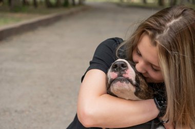 Beyaz kadın portresi açık havada köpeğine sarılıyor.