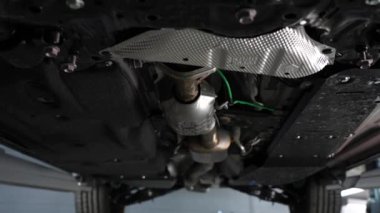 Otomobil tamircisi bir kadın, kollarını göğsüne bağlamış bir arabanın açık kaputunda duruyor.