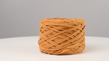 Beyaz arka planda dönen hardal renkli pamuk yumağı.