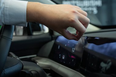 Bir adam yeni bir arabanın ön panelinden koruyucu filmi çıkarır.