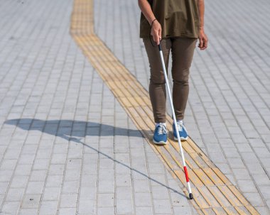 Yaşlı, kör, bastonlu, dokunmatik bir kadının bacaklarına yakın çekim.