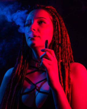 Rastalı beyaz kız kırmızı ışıkta sigara içiyor.