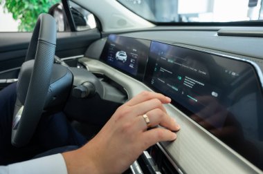 Modern bir arabanın torpido gözüne yakın çekim yapan bir adam.