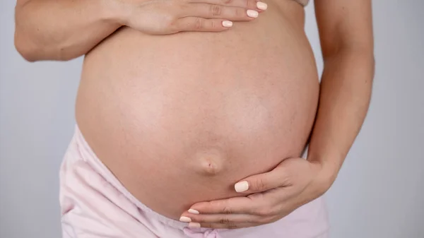 白い背景の第三期の妊婦の腹のクローズアップ — ストック写真