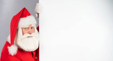 Noel Baba boş bir Noel reklamının arkasından bakıyor.