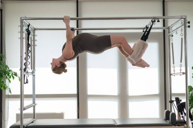 Reformcuda pilates yapan hamile bir kadın.