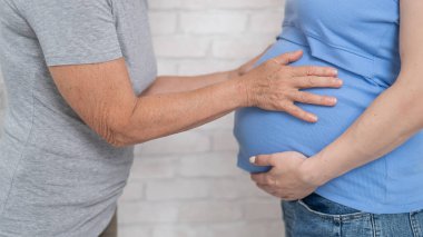 Yaşlı bir kadın hamile kızının karnına dokunur. Yakın plan.