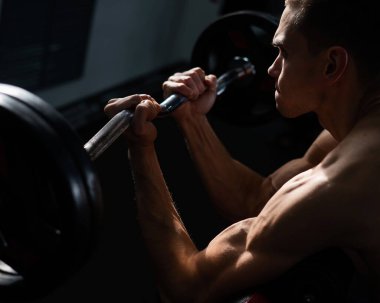 Man doing EZ barbell bicep exercises on Scott bench
