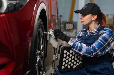 Kadın bir oto tamircisi bir camber yapar. Araba servisinde çalışan bir kadın.