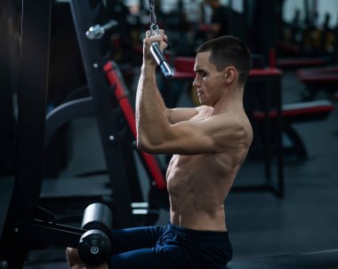 A man does a chest pulldown in the gym