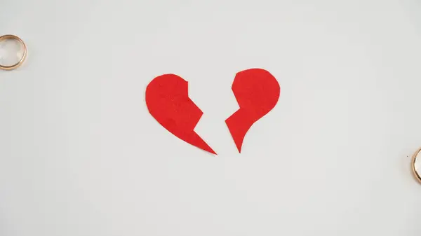 Broken heart and wedding rings on a white background. Divorce concept