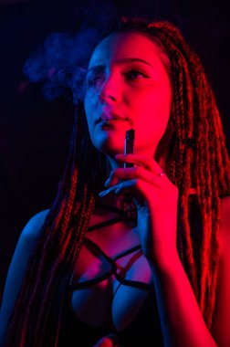 Rastalı beyaz kız kırmızı ışıkta sigara içiyor.