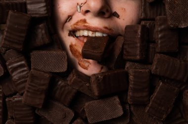 The face of a caucasian woman surrounded by sweets. The girl is smeared in sweets