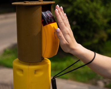 Kör bir kadının eli trafik ışığı için düğmeye basıyor.