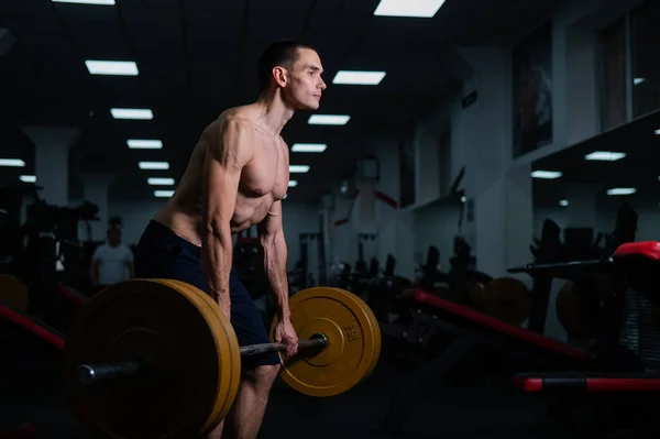 stock image Shirtless man doing bicep exercises with dumbbells in the gym