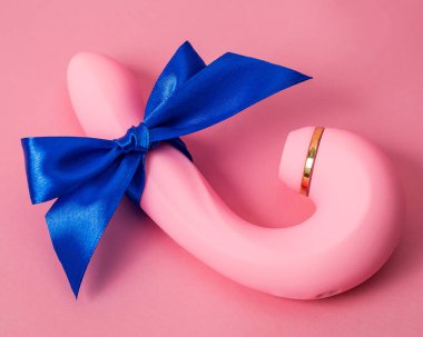 Curved dildo with blue ribbon on pink background