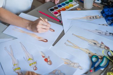 Yüzü olmayan kadın mayo çizimleri çiziyor. Bir moda tasarımcısının ellerine yakın çekim