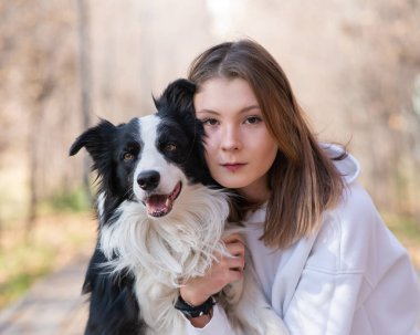 Sonbahar parkında sınır köpeğini kucaklayan beyaz bir kadın. Köpekli bir kızın portresi.