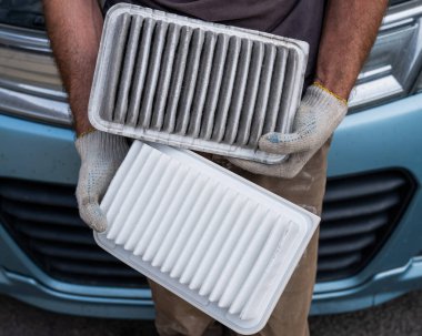 Araba motorundaki hava filtresini değiştiriyor.