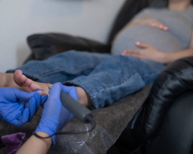 Güzellik salonunda hırdavat pedikür yapan hamile bir kadın.