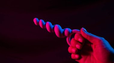 Neon pembe ışıkta anal boncuklar tutan bir kadın. Boşluğu kopyala