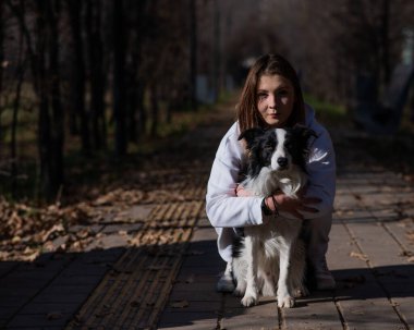 Sonbahar parkında sınır köpeğini kucaklayan beyaz bir kadın. Köpekli bir kızın portresi.