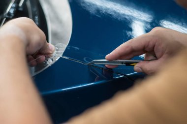 Araba servisindeki usta koruyucu kesiciyi kesiyor.