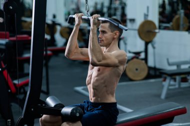 A man does a chest pulldown in the gym