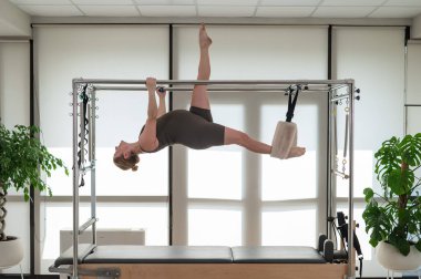 Hamile bir kadın bir reformcu üzerinde pilates yapıyor. Hava jimnastiği