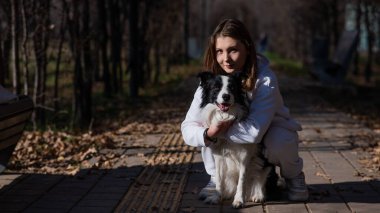 Sonbahar parkında sınır köpeğini kucaklayan beyaz bir kadın. Köpekli bir kızın portresi.