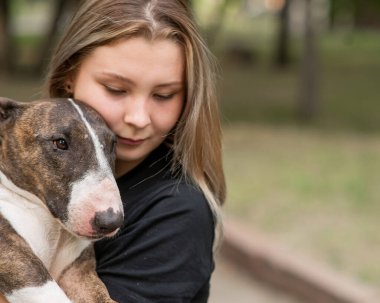 Beyaz kadın portresi açık havada köpeğine sarılıyor.