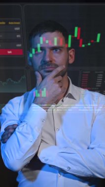 Kafkasyalı adam karanlıkta sanal bir ekrana bakıyor. Borsa tabloları. Dikey video