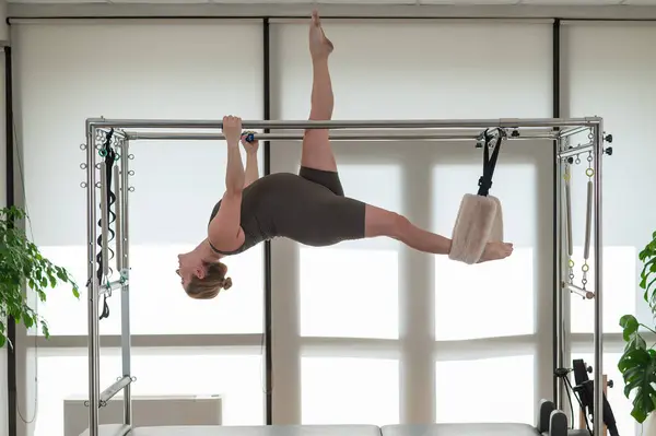 A pregnant woman is doing Pilates on a reformer. Aerial gymnastics