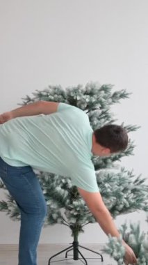 Beyaz bir adam yapay bir Noel ağacını söküyor. Dikey video. Zaman aşımı