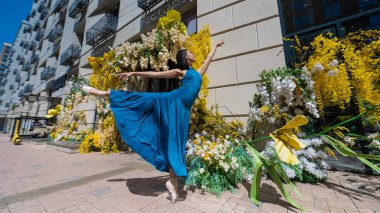 Çiçeklerle süslenmiş bir binanın arka planında poz veren güzel bir Asyalı balerin.