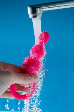 Mavi arka planda akan suyun altında pembe anal boncuklar tutan bir kadın. Seks oyuncağı hijyen konsepti