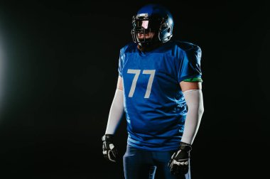 Stüdyoda mavi Amerikan futbol üniformalı, kızıl sakallı bir Asyalı.