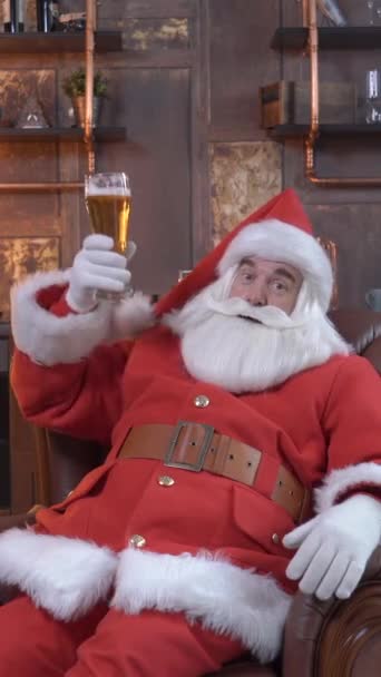 Der Weihnachtsmann Stößt Mit Einem Becher Bier Und Sitzt Auf — Stockvideo