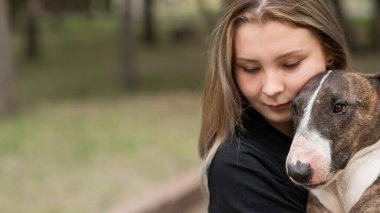 Beyaz kadın portresi açık havada köpeğine sarılıyor.