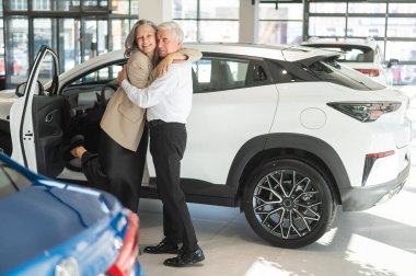 Olgun, beyaz bir çift sarılıyor. Yaşlı adam ve kadın yeni bir araba satın alıyorlar.