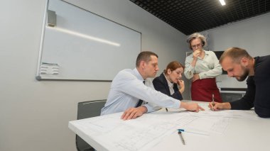 The female boss evaluates the work of subordinates. Designers engineers at a meeting