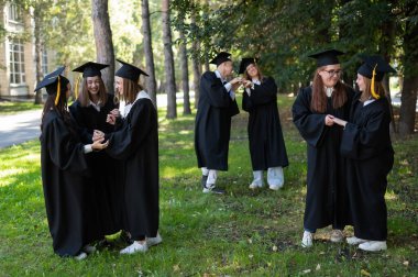 Bir grup bornoz içinde mezuniyetleri için birbirlerini kutluyorlar.